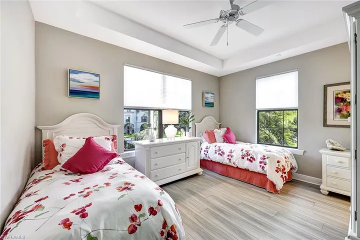Bedroom featuring a tray ceiling, ceiling fan, and light wood-type flooring