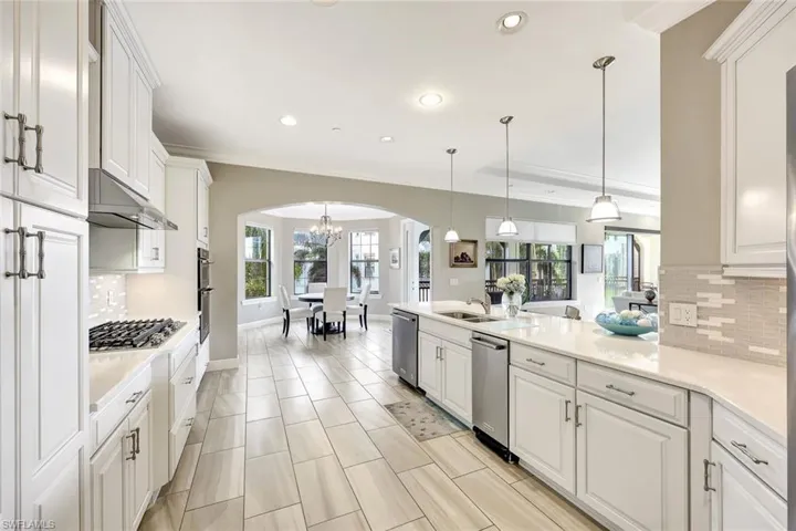 Kitchen with tasteful backsplash, stainless steel appliances, sink, decorative light fixtures, and white cabinetry