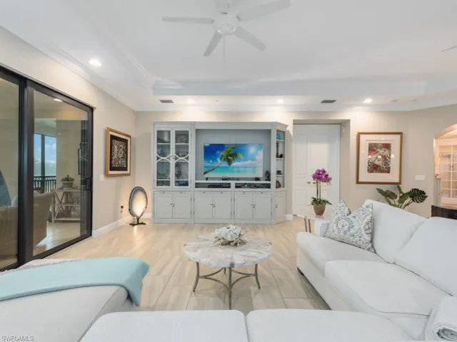 Living room with a tray ceiling, crown molding, ceiling fan, and light hardwood / wood-style flooring