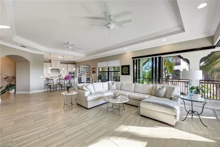 Living room with ceiling fan, crown molding, and a tray ceiling