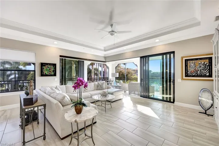 Living room featuring ceiling fan, a raised ceiling, ornamental molding, and light hardwood / wood-style flooring