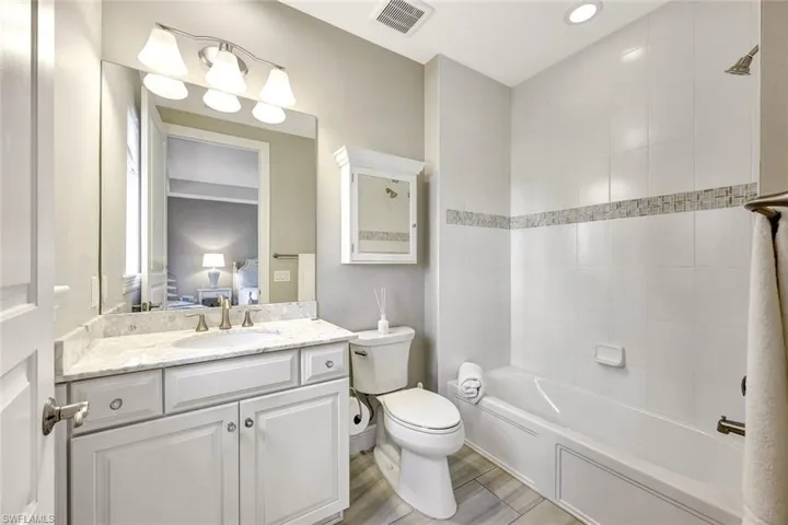 Full bathroom with vanity, wood-type flooring, tiled shower / bath and toilet