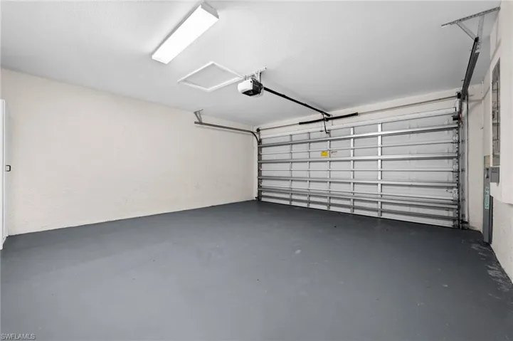 Attached garage with a roll-up door, overhead lighting, and an access door