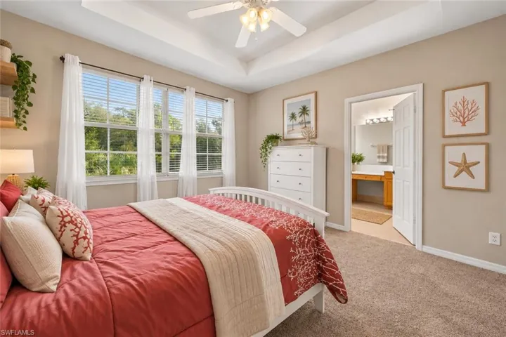 Tray ceiling with a ceiling fan, three paneled windows with blinds, and carpet flooring