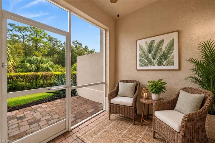 Screened outdoor space with textured wall, paver flooring, and lush perimeter landscaping