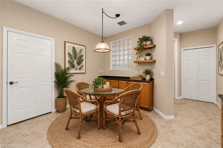 Dining area with tiled flooring, suspended lighting, and a built-in wood-finish cabinet with a dark countertop