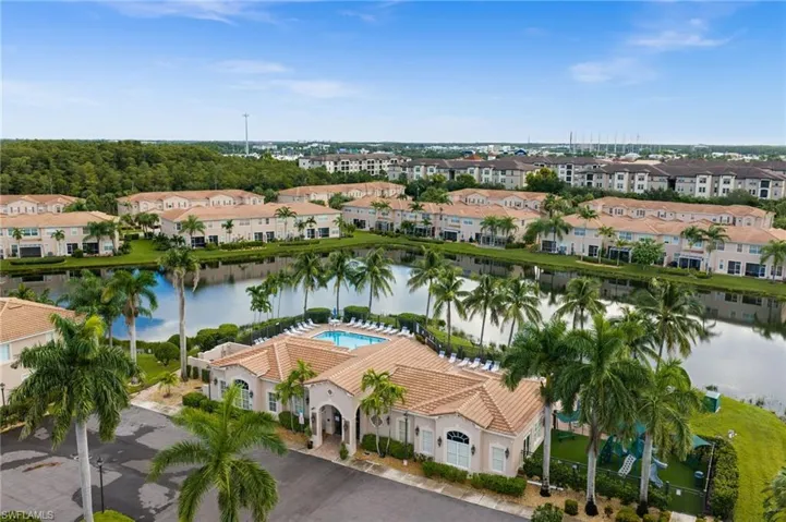 Community clubhouse with an outdoor swimming pool, surrounded by mature palm trees and a reflective pond
