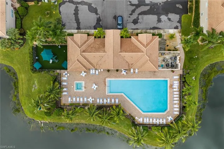 Expansive community pool with an integrated spa, surrounded by a paved deck with lounge seating