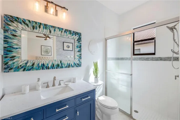 EN SUITE DOWN STAIRS Bathroom featuring a shower with shower door, vanity, ceiling fan, and toilet