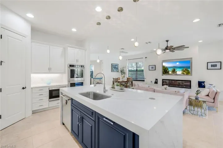 Kitchen with blue cabinets, white cabinets, sink, a center island with sink, and appliances with stainless steel finishes