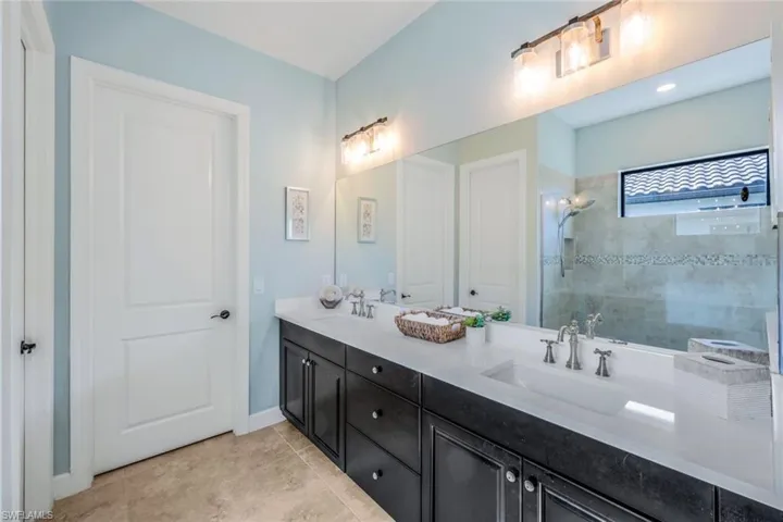 Bathroom featuring a shower with shower door, tile patterned floors, and double sink vanity