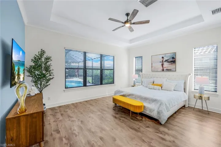 MASTER Bedroom with ceiling fan, a tray ceiling, and wood-type flooring