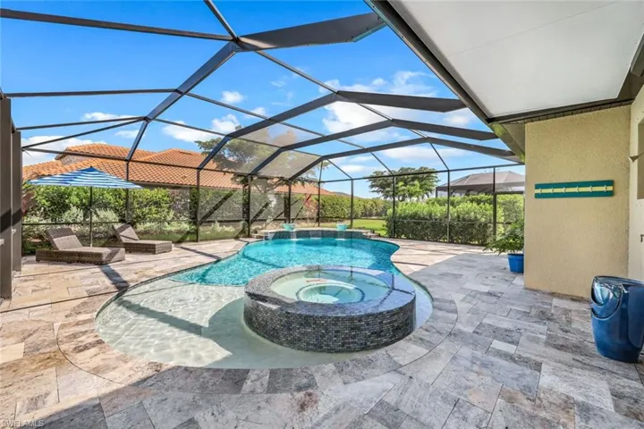 View of swimming pool with an in ground hot tub, a patio area, pool water feature