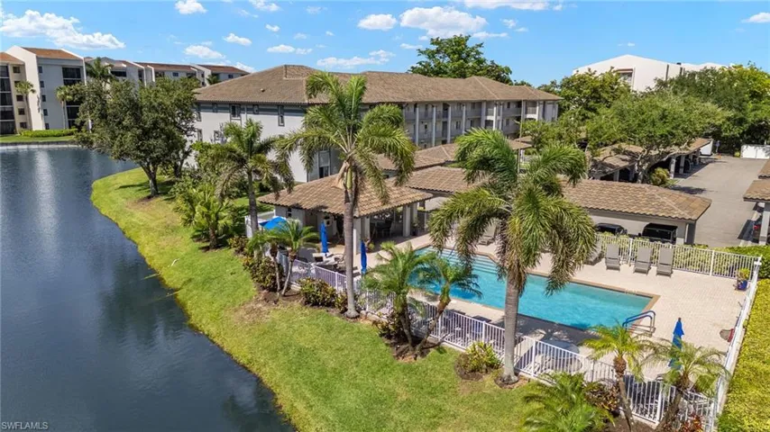 Aerial view of residential area featuring a nearby body of water and a pool