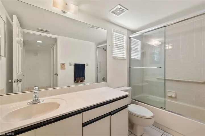 Full bathroom with tile patterned flooring, toilet, vanity, and combined bath / shower with glass door