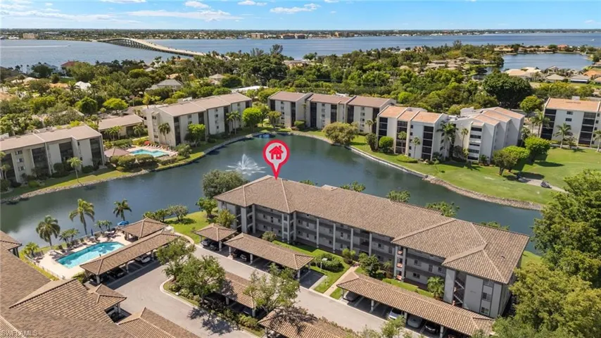 Drone / aerial view of a large body of water, apartment complex / building, and a pool area