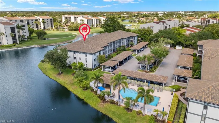 Drone / aerial view of a large body of water, apartment complex, and a pool area