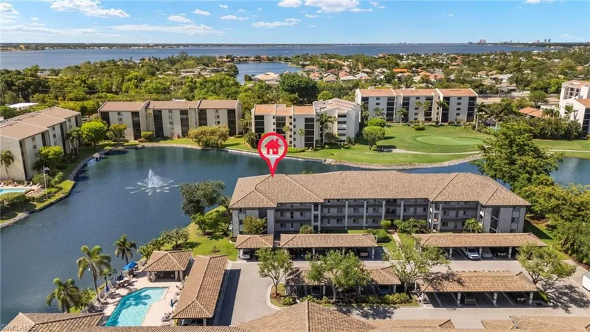 Drone / aerial view of apartment complex / building, a nearby body of water, a golf course, and a pool