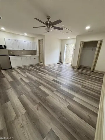 Wood-finish flooring, recessed lighting, ceiling fan, white cabinetry, and an open closet space