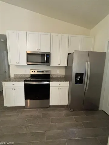 White shaker-style cabinetry with dark hardware, light countertop, stainless steel sink, and wood-finish flooring
