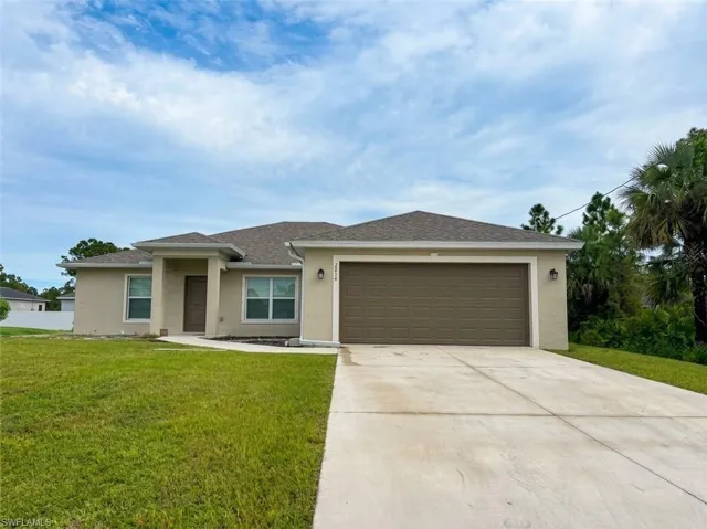 Stucco exterior with a covered entry, attached garage, concrete driveway, and a shingle roof