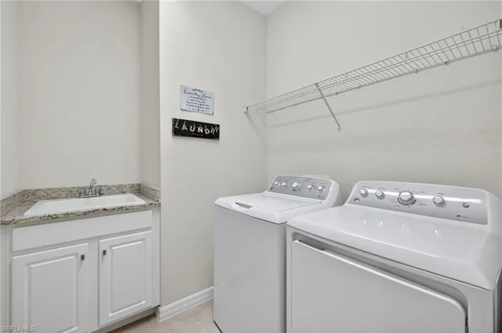Laundry area with independent washer and dryer, cabinet space, and light tile patterned floors