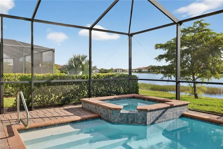 View of swimming pool with a sunroom, a water view, glass enclosure, and a pool with connected hot tub
