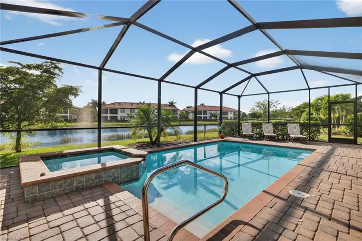 View of swimming pool with a water view, a sunroom, a lanai, a pool with connected hot tub, and a patio area