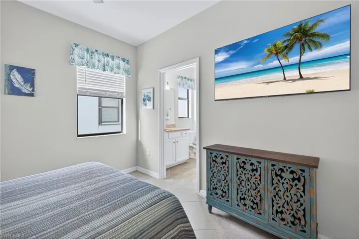 Bedroom with ensuite bath and light tile patterned flooring