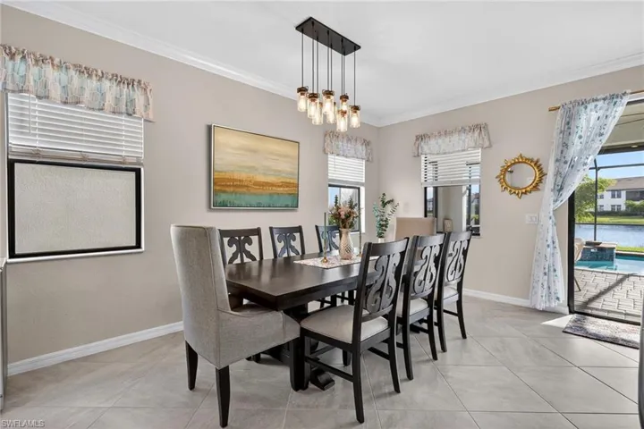 Dining room featuring ornamental molding, light tile patterned floors, and a water view