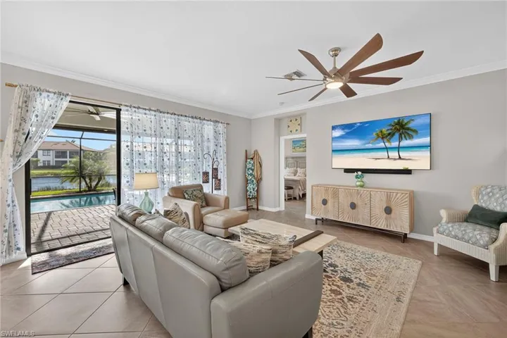 Living area featuring ceiling fan, a water view, ornamental molding, and light tile patterned flooring