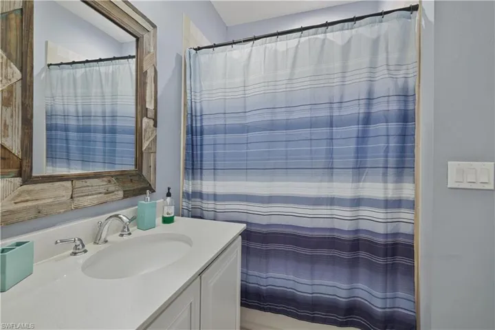 Bathroom featuring curtained shower and vanity