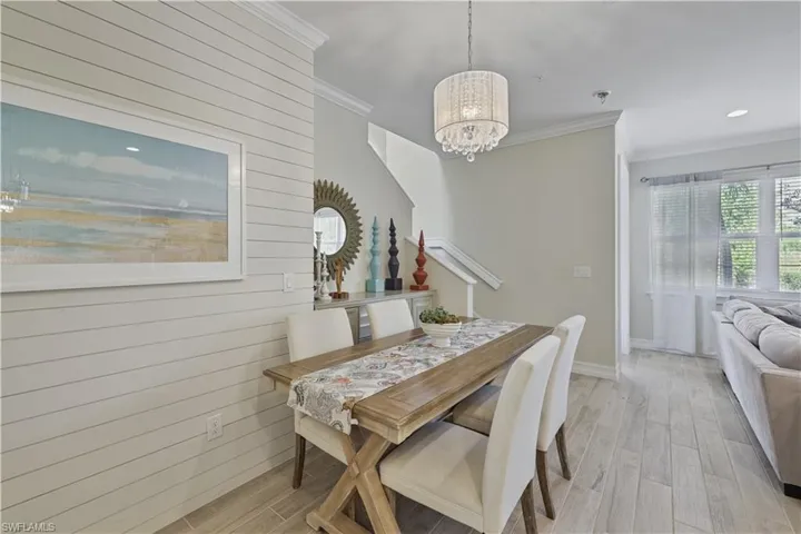 Dining space with wood finish floors, ornamental molding, wooden walls, and a chandelier