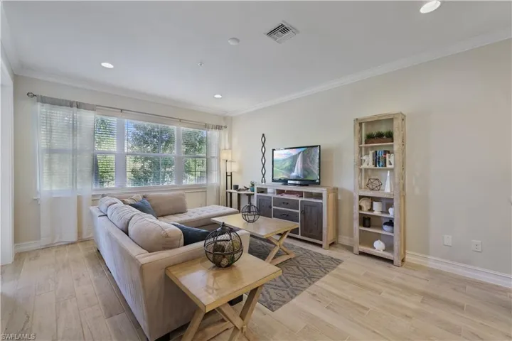 Living area with light wood-type flooring, crown molding, and recessed lighting