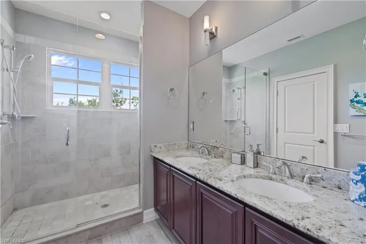 Full bathroom featuring double vanity and a shower stall