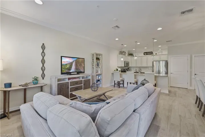 Living room with recessed lighting, ornamental molding, and light wood-type flooring