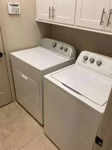 Dedicated laundry area featuring white upper cabinetry with brushed nickel hardware, a built-in shelf, and tile flooring