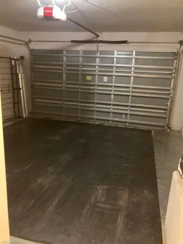 Attached garage space featuring a roll-up garage door, automatic garage door opener, and concrete flooring
