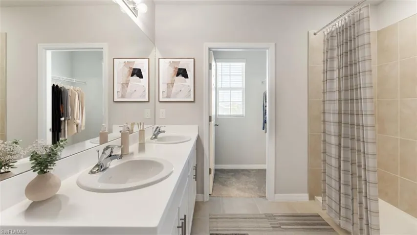 Bathroom with light tile patterned flooring, double vanity, and a tile shower