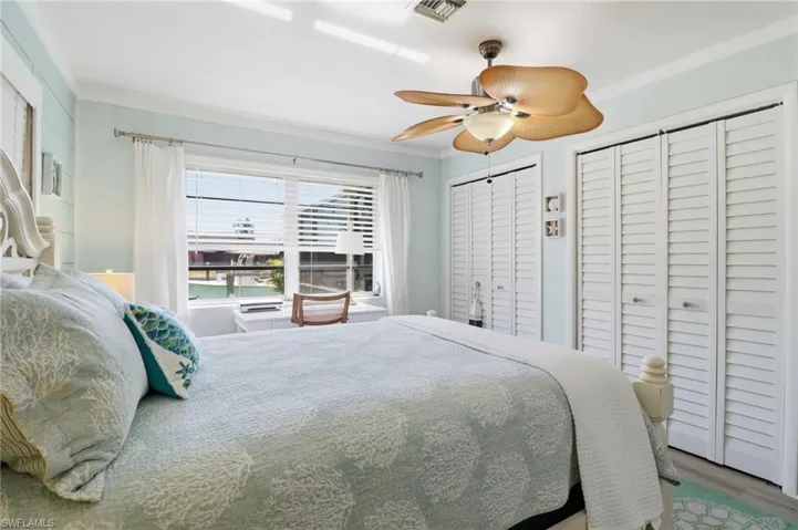 Bedroom with two closets, crown molding, ceiling fan, and wood finished floors