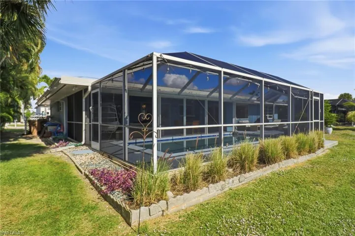 View of property exterior featuring a lawn, a sunroom, an outdoor pool, and a lanai