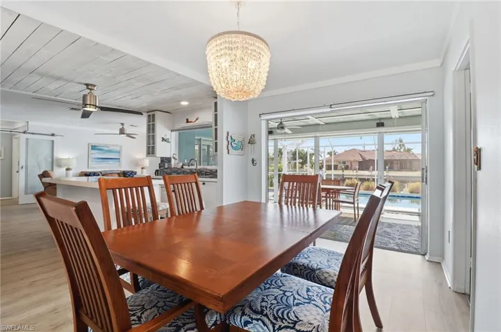 Dining room featuring a chandelier, a ceiling fan, wooden ceiling, a barn door, and a sunroom