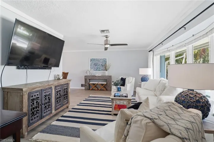 Living area with crown molding, wood finished floors, and ceiling fan