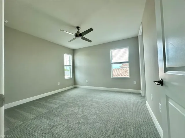 Carpeted spare room with plenty of natural light and ceiling fan