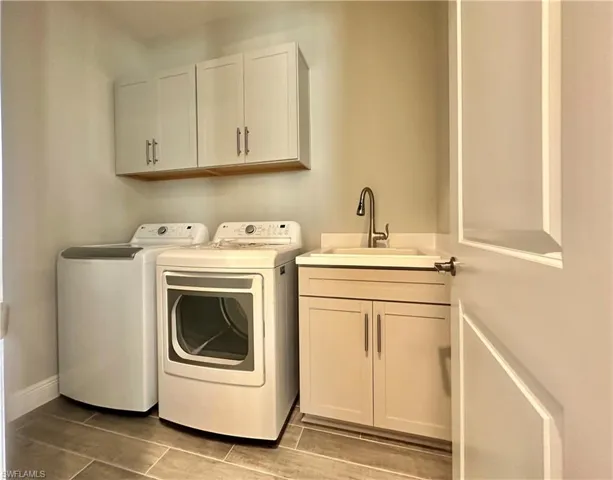 Laundry area with washer and clothes dryer, cabinet space, and wood tiled floors