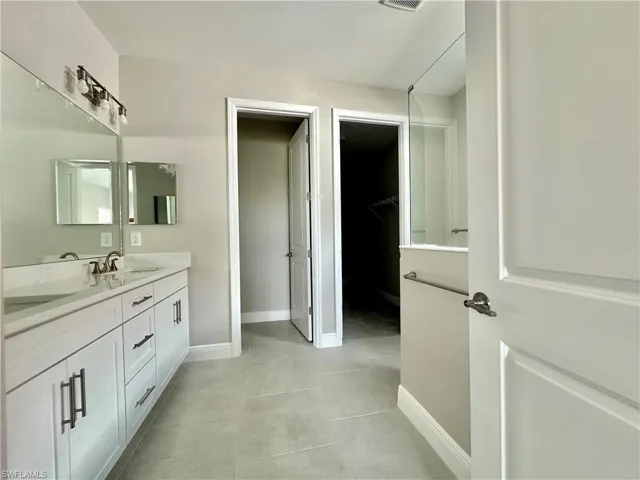 Full bath featuring double vanity and a spacious closet