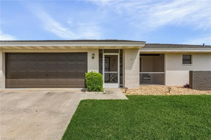 Ranch-style home featuring a garage and a front lawn