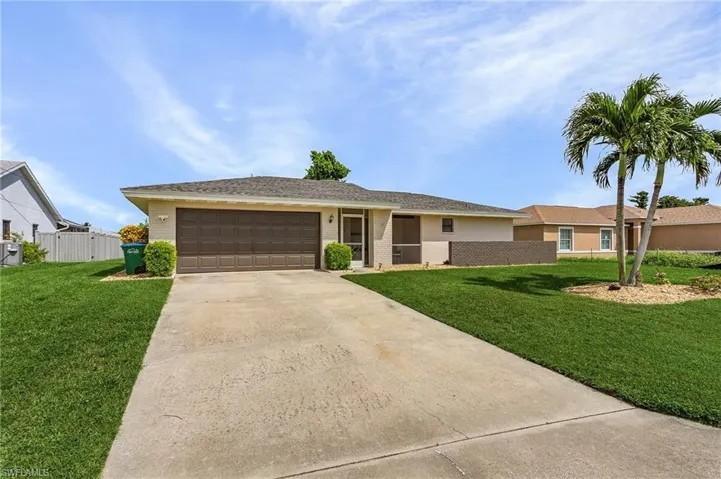 Single story home with a garage and a front lawn