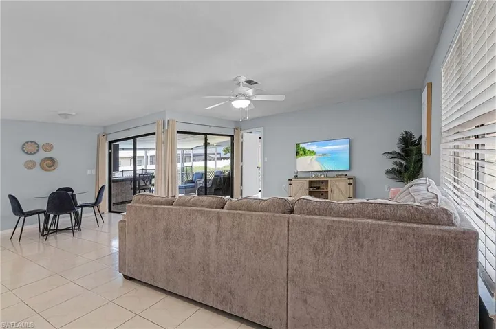 Living room with ceiling fan and light tile patterned flooring
