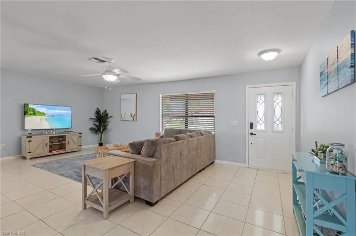 Living room with ceiling fan and light tile patterned floors
